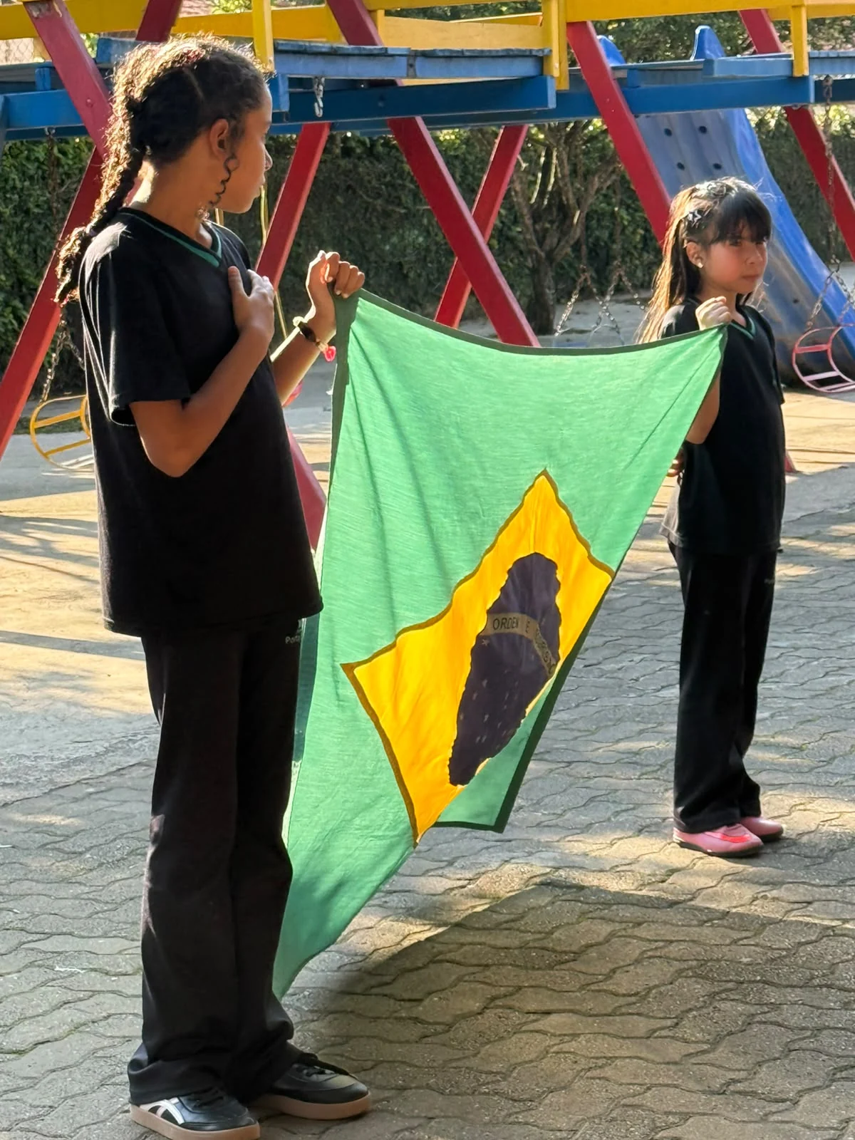 Estudantes com a bandeira do Brasil no pátio do colégio